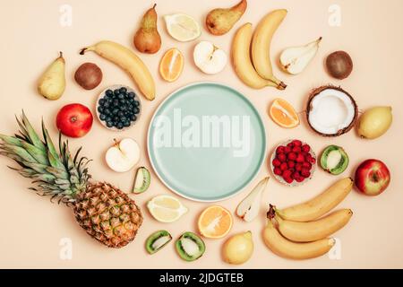 Various fruits on yellow background, blue plate in a center. Top view, flat lay, mockup. Tropical fruits, vegan food, healthy diet. Stock Photo