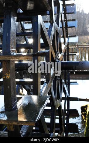 Closeup of old wooden watermill wheel against nature background Stock Photo