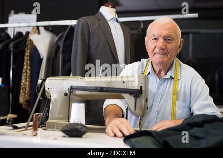 Portrait of elderly tailor working on sewing machine at studio Stock Photo