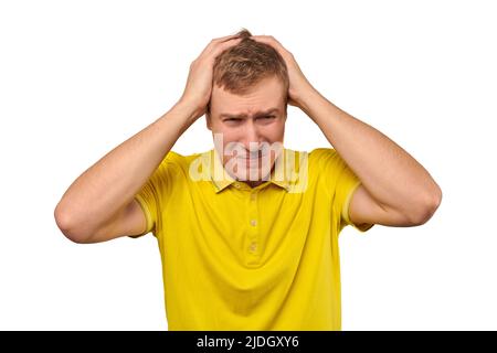 Upset man in yellow T-shirt clutched at his head, forgetful man with headache isolated on white background. Young guy worried and frustrated, grabbed Stock Photo