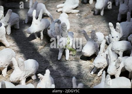 White rabbit statues made of plaster at outdoor art exhibition, artificial white hares on city street. A lot of white handmade rabbits, many decorativ Stock Photo