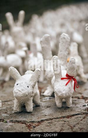 White rabbit statues made of plaster at outdoor art exhibition, artificial white hares on city street. A lot of white handmade rabbits, many decorativ Stock Photo