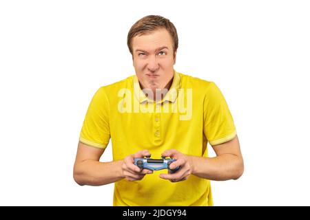 Funny attractive gamer in yellow T-shirt with gamepad isolated on white background. Cheerful young guy holding joy stick and playing videogames on TV, Stock Photo