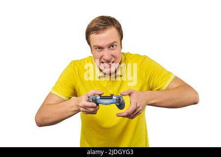 Funny attractive gamer in yellow T-shirt with gamepad isolated on white background. Cheerful young guy holding joy stick and playing videogames on TV, Stock Photo