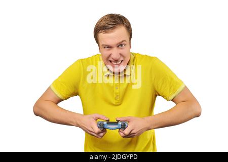 Funny attractive gamer in yellow T-shirt with gamepad isolated on white background. Cheerful young guy holding joy stick and playing videogames on TV, Stock Photo