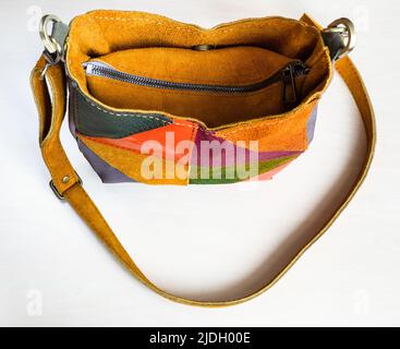 above view of closed handcrafted patchwork cross body bag hand sewn from yellow suede on white background Stock Photo