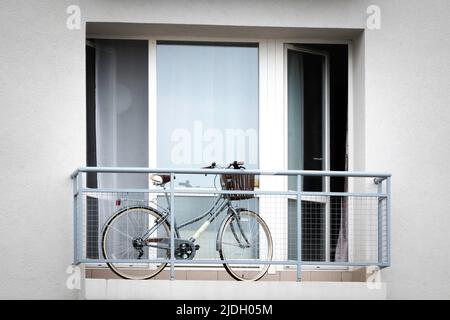 Bicycle with basket on balcony. Storage of bicycle on open balcony in apartment building Stock Photo