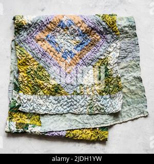 folded patchwork scarf sewn from various crinkled silk fabrics on gray conctete backhround Stock Photo