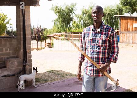 African American Young Male Farmer Checking Smartphone Among Green 