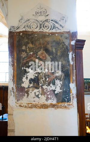 The remains of the fresco depicts a figure in a nun's habit, carrying a crucifix and showing stigmata on her hands.. Inside the Church of Saint Vorles Stock Photo