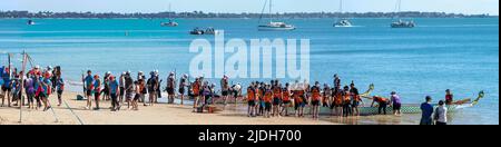 Teams on a sandy beach preparing to compete in a Dragon Boat race. Scarness Hervey Bay Queensland Australia Stock Photo