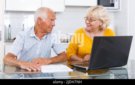 Mature man and woman discussing while working at laptop together Stock Photo