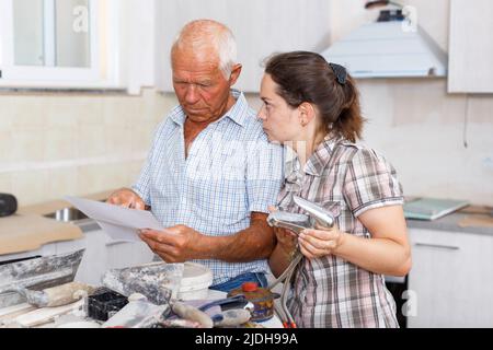 Woman and father discussing instructions for mixer tap Stock Photo