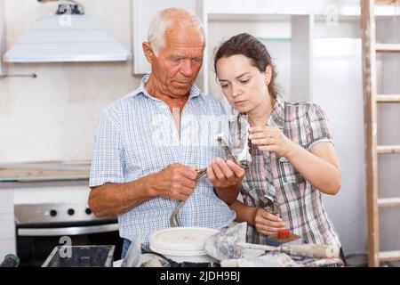 Woman and elderly father discussing installing faucet Stock Photo
