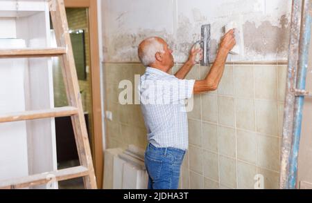 Old worker with plastering tools Stock Photo