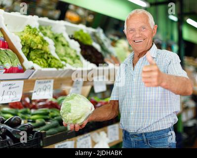 Portrait of happy elderly man giving thumbs up, satisfied with fresh products Stock Photo