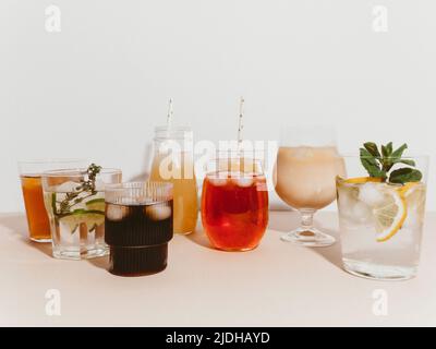 Various refreshing non-alcoholic drinks in glasses with ice. Different juice, homemade lemonade, iced coffee, iced fruit tea and smoothies on light ba Stock Photo