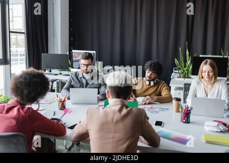 multicultural advertising managers working near laptops in meeting room Stock Photo