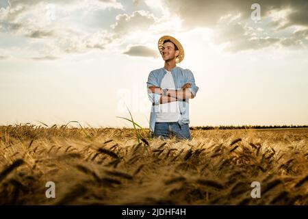 Happy farmer is standing in his growing barley field. Stock Photo