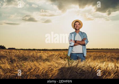 Happy farmer is standing in his growing barley field. Stock Photo