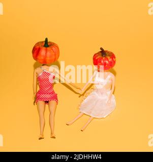 Halloween funny concept made of girl dolls with pumpkins. Minimal holiday concept. Stock Photo