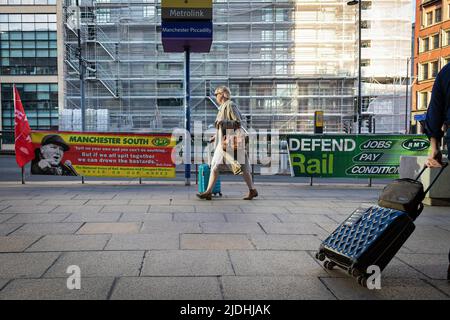 Manchester, UK. 21st June, 2022. A member of the public walks past RMT banners. The biggest rail strike in over 30 years went ahead after last-minute talks failed. RMT states it has no choice but to strike due to proposed cuts to jobs, pay and pensions. Credit: SOPA Images Limited/Alamy Live News Stock Photo