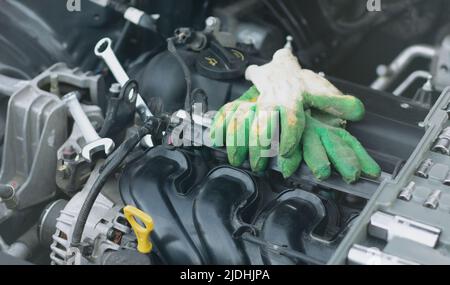 Wrenches and work gloves lie on the car engine in the engine compartment. Stock Photo