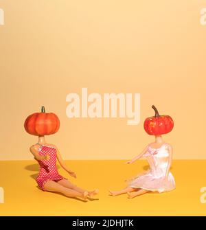 Halloween funny concept made of girl dolls with pumpkins. Minimal holiday concept. Halloween idea. Stock Photo