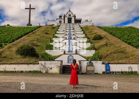 a lady in a red dress contemplates the ceramic decorated staircase to the chapel of nossa senhora do paz Stock Photo