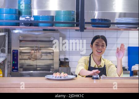 Woman gesturing with hand touching bell on bar counter Stock Photo