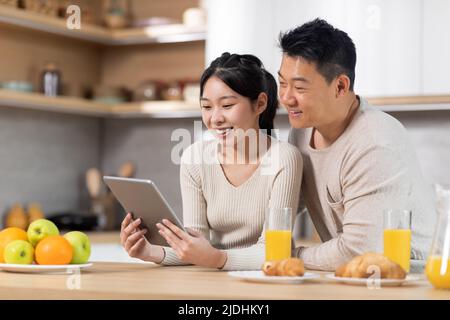 Happy chinese family using digital tablet while having breakfast Stock Photo