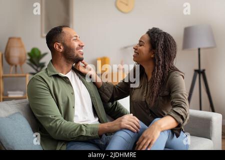 Happy Black Couple Sitting And Hugging At Home Stock Photo