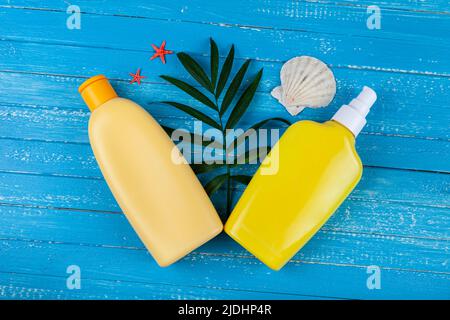 Flat lay composition with sunscreen and seashells on a blue wooden background. Stock Photo