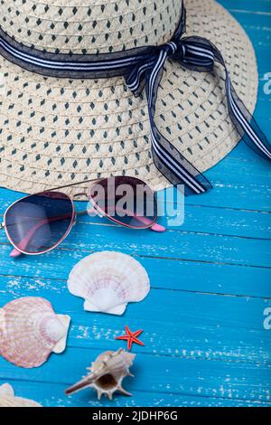 Composition with hat, sunglasses and seashells on a blue wooden background. Stock Photo