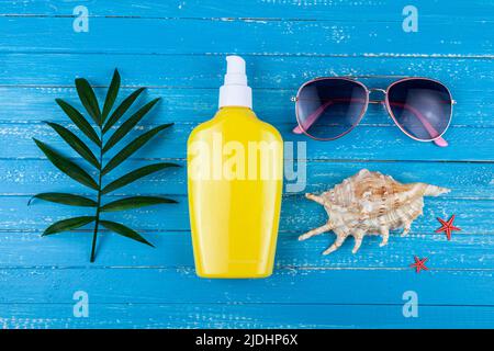 Flat lay composition with sunscreen and seashells on a blue wooden background. Stock Photo