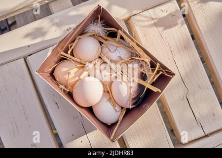 Organic white chicken eggs in a box with straw and feathers Stock Photo