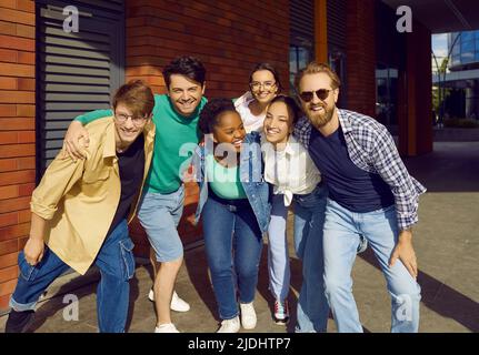 Joyful group of multiracial friends are having fun and fooling around walking streets of city. Stock Photo