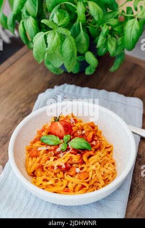 Served plate of just cooked homemade fettuccine pasta with creamy tomato sauce, seafood and parmesan cheese, decorated with basil leaves and cherry to Stock Photo