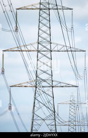 UK Electricity pylon lattice tower close up of structure and wires leading to next pylon in the line. Stock Photo