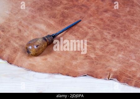 Leather craft tools on a wooden background. Leather craftmans work desk . Piece of hide and working handmade tools on a work table Stock Photo