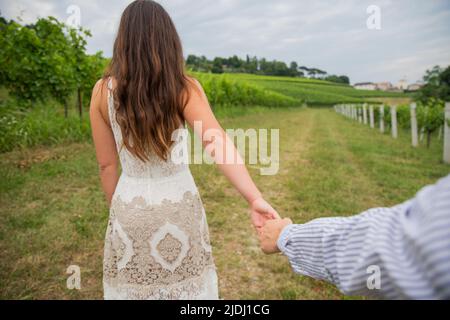 Boyfriend holds his girlfriend by the hand, they lie in a vineyard, romantic moment, couple in love Stock Photo