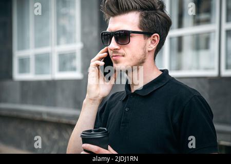 Young man in sunglasses is talking on a smartphone. Stock Photo