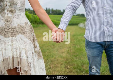 Close-up of the hands of a couple holding hands outside in a vineyard Stock Photo