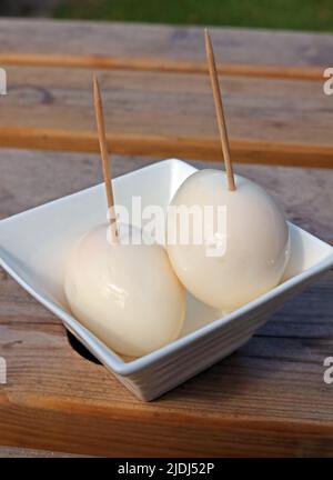 Two malt vinegar pickled eggs on a British pub table, a tasty snack with beer in a British pub beer garden, eaten using a cocktail stick Stock Photo