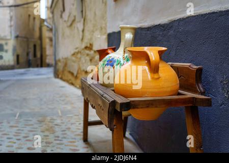 Antique wooden furniture with brightly colored clay pots in a medieval town. Spain. Stock Photo