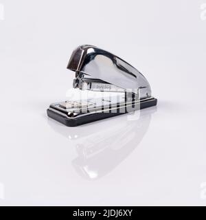 Metallic stapler for stapling sheets of paper with reflection on white background. Stock Photo
