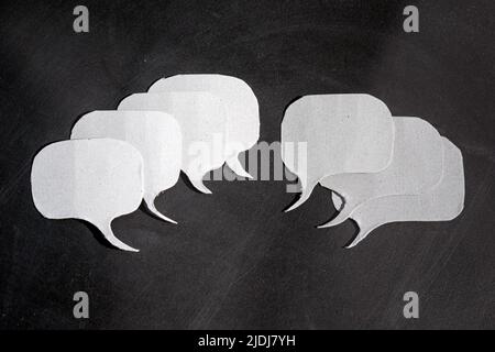 Pros and cons.Group of speech bubbles cut out of cardboard with multiple blank dialogue frames. Stock Photo
