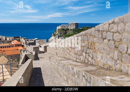 Fort Lovrijenac rises above the city wall as the path slopes downward - Old Town Dubrovnik Stock Photo