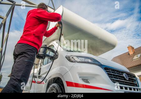 Male Traveler Thoroughly Washing His Big White RV Camper at Touchless Self-Service High Pressure Car Wash. Recreational Vehicle Care and Maintenance T Stock Photo