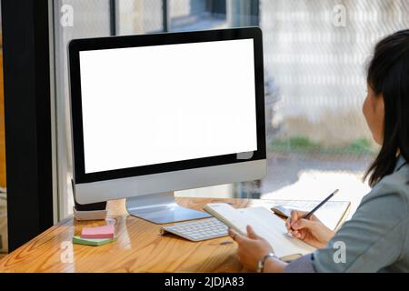 A white screen computer placed on the desk at work. Can put text or media in the area on the white scren Stock Photo